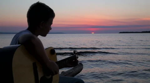 Boy plays on guitar at sunset Stock Footage 67239062