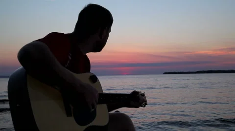 Boy plays on guitar at sunset Stock Footage 67239139