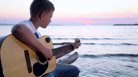 Boy plays on guitar at sunset Stock Footage 67529238