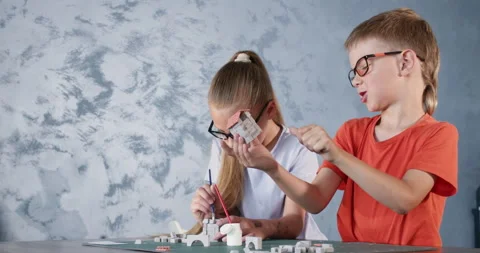 Boy plays with house of clay bricks sitting near sister Stockbeeldmateriaal 285329264