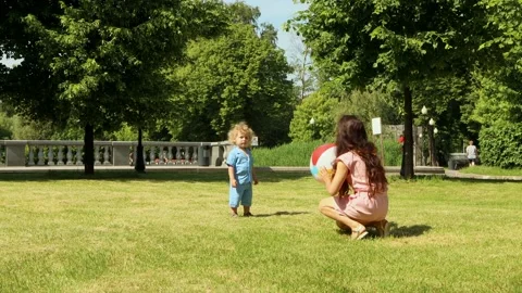 A boy plays inflatable ball with his mother in the Park Sunny summer day, 4K Stock Footage 133905902