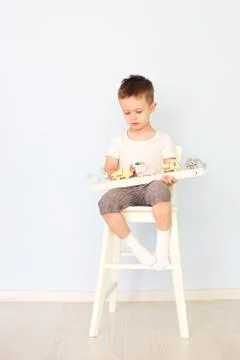 A boy plays with a machine and sits on the chair Stock Photos