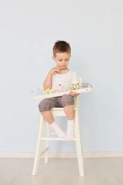 A boy plays with a machine and sits on the chair Stock Photos
