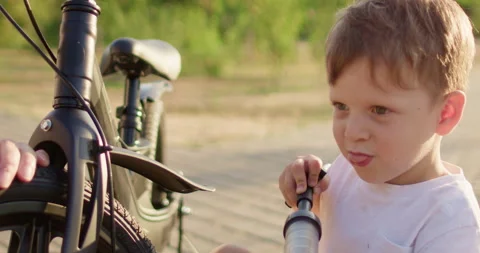 Boy plays with manual pump preparing bicycle for riding Stock Footage 316763877