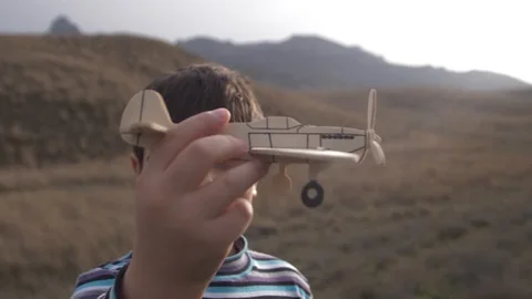 The boy plays the model of the plane against the background of the mountains Stock Footage 88439012