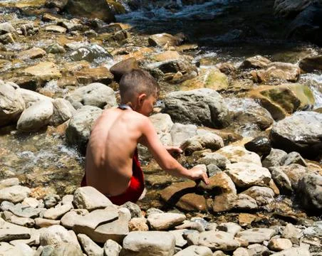 The boy plays in a mountain stream. The mountains. Stones. Autumn. sunny day Stock Photos