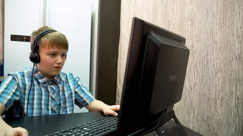 The boy plays an online game on a computer through an Internet monitor with head Stock Footage 99223067