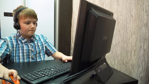 The boy plays an online game on a computer through an Internet monitor with head Stock Footage 99223222