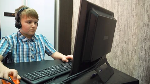 The boy plays an online game on a computer through an Internet monitor with head Stock Footage 99223490