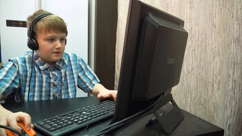 The boy plays an online game on a computer through an Internet monitor with head Stock Footage 99223625