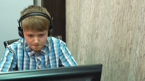 The boy plays an online game on a computer through an Internet monitor with head Stock Footage 99223713