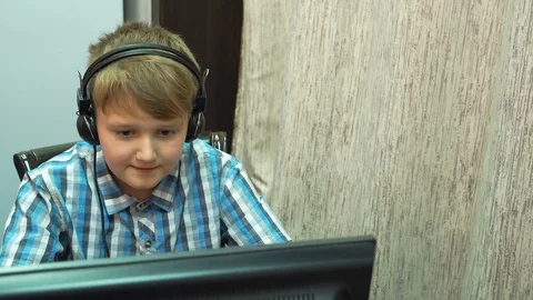 The boy plays an online game on a computer through an Internet monitor with head Stock Footage 99223924