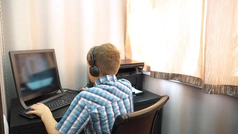 The boy plays an online game on a computer through an Internet monitor with head Stock Footage 99224577