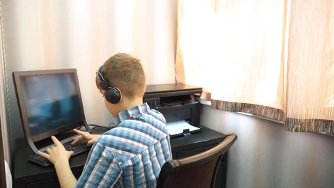 The boy plays an online game on a computer through an Internet monitor with head Stock Footage 99224785