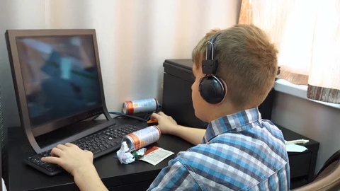 The boy plays an online game on a computer through an Internet monitor with head Stock Footage 99225035
