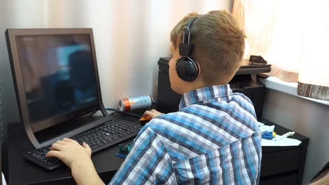 The boy plays an online game on a computer through an Internet monitor with head Stock Footage 99225370