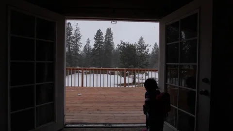 Boy Plays by Open Door Facing Snow Video stock 76014403
