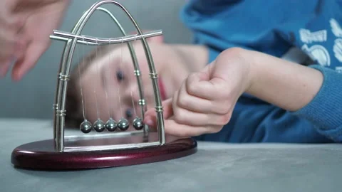 Boy plays with pendulum newton's balls Stock Footage 146798638