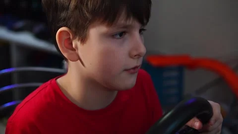Boy plays racing simulator on computer steering wheel. Video stock 297451036