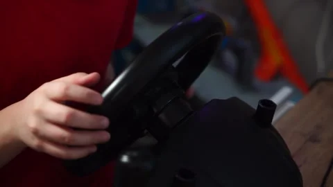 Boy plays racing simulator on computer steering wheel. 库存影片 297451104