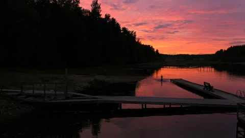 Boy plays in the river at the evening with dramatic sunset background Video stock 129938581