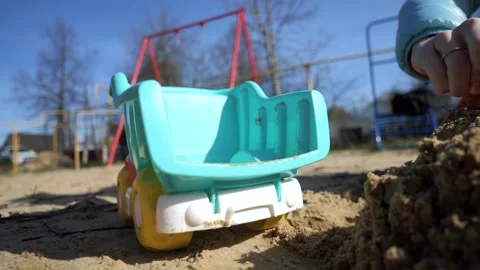A boy plays in the sandbox with a tractor and a truck, loads them with sand usin Stock Footage 273281189