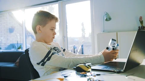 Boy plays with a small robot and day dreams as the sun shines through windows Stock Footage 102182659