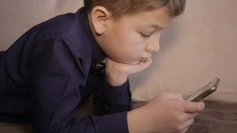 A boy plays on the smartphone Vídeos de archivo 71944138