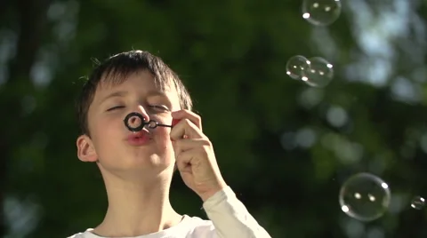 The Boy Plays with Soap Bubbles in Park Video stock 62910915