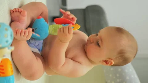 The boy plays with a soft toy on the floor. vertical video Stock Footage 248357221