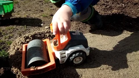 A boy plays with a toy compactor on the sand Stock Footage 220113676