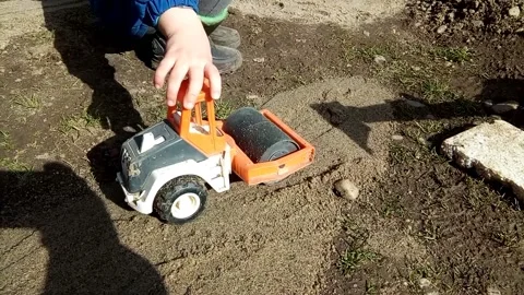 A boy plays with a toy compactor on the sand Stock Footage 220113677