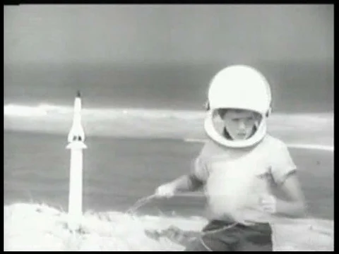 A boy plays with a toy rocket, at the beach, with his mom and dad, in a Stock Footage 74934272
