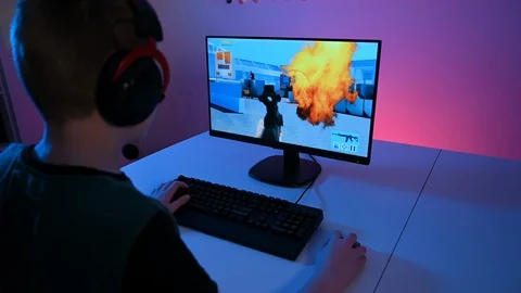 Boy plays video game on computer online while sitting at home at night Stock Footage 100725684