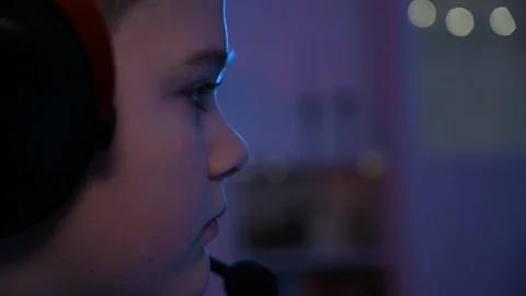 Boy plays video games while wearing headphones - close up of face Stock Footage 100793466