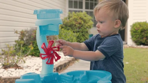 Boy plays with water table spinner in slow motion  Stock Footage 129896313