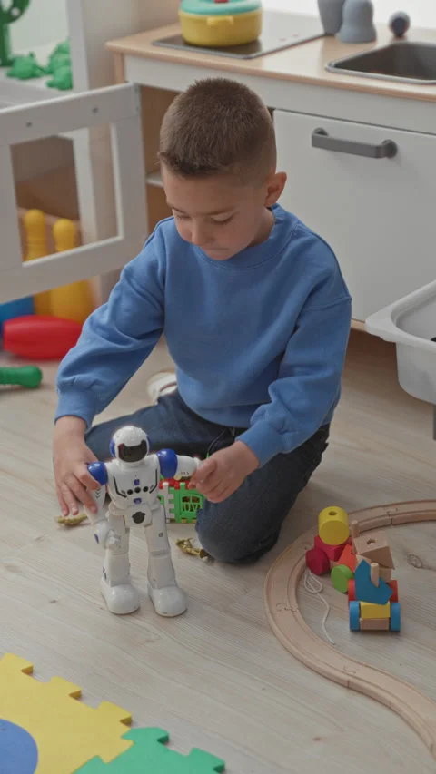 Boy plays with white robot toy on wooden floor in a playroom, hands adjusti.. Stock Footage 339155205