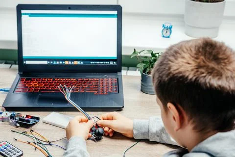 A boy plugging cables to sensor chips while learning arduino coding and robotics Stock Photos