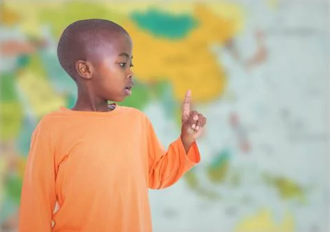 Boy pointing against blurry map Fotos de archivo
