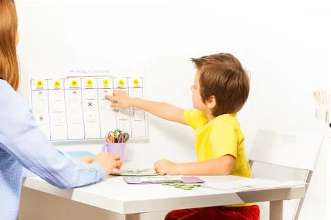 Boy points at activities on calendar learning days Stock Photos