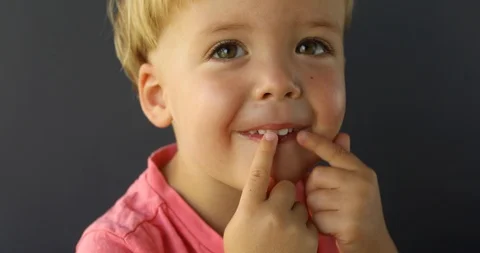 Boy points his fingers of both hands on his teeth Stock Footage 101668103