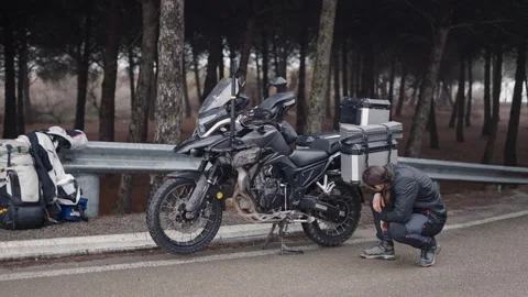 A boy with a ponytail checking something on his motorbike Stock Footage 271088405