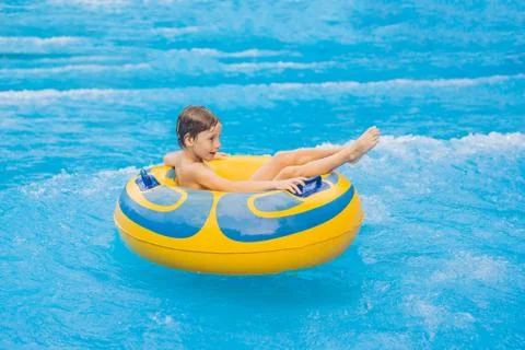 Boy on a pool float on artificial waves in a water park Stock Photos