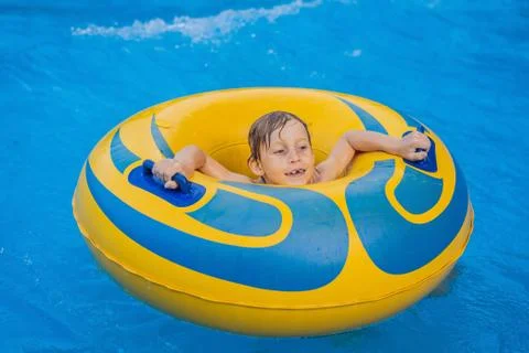 Boy on a pool float on artificial waves in a water park Foto stock