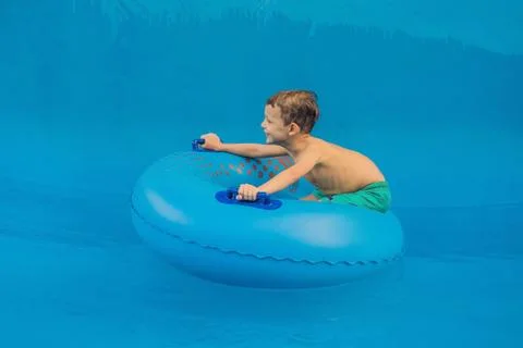 Boy on a pool float on artificial waves in a water park Stock Photos
