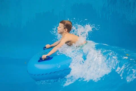 Boy on a pool float on artificial waves in a water park Stock Photos