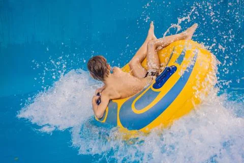 Boy on a pool float on artificial waves in a water park Stock Photos