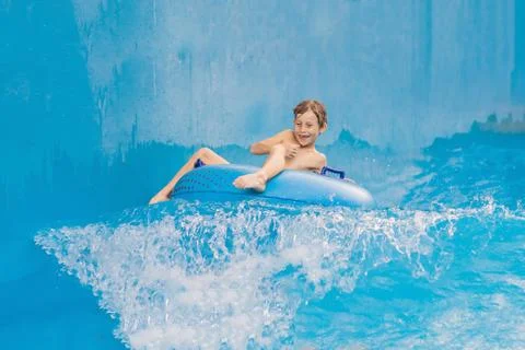 Boy on a pool float on artificial waves in a water park Foto stock