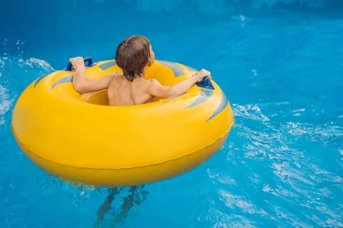 Boy on a pool float on artificial waves in a water park 스톡 사진