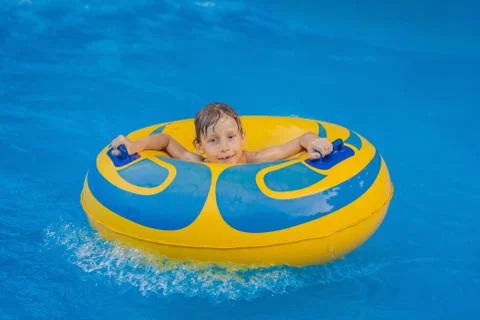 Boy on a pool float on artificial waves in a water park Stock Photos